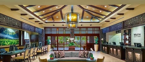 A spacious lobby with a reception desk, seating area, and a large window providing a view of the outdoors.