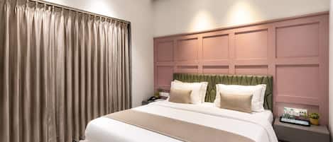 Un dormitorio moderno con una cama grande, cabecera con diseño geométrico, mesita de noche con lámpara y ventana con cortinas.