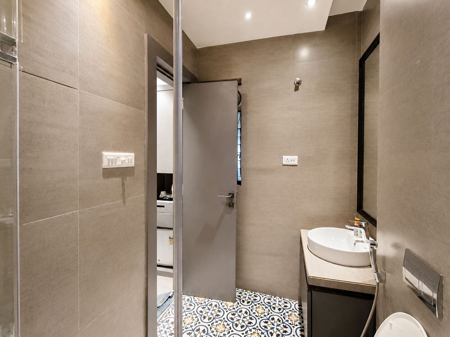 Un baño moderno con ducha, lavamanos y espejo.