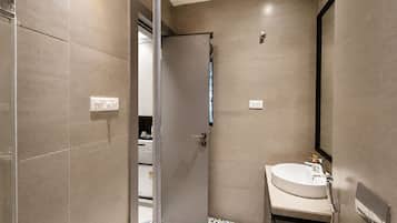 Un baño moderno con ducha, lavamanos y espejo.