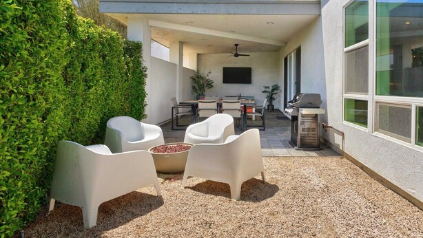 Uma área de terraço ao ar livre com churrasqueira, assentos e ventilador de teto.
