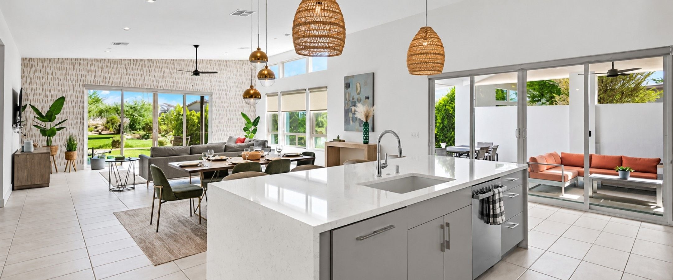 A modern kitchen with a large island, dining area with a table and chairs, and a living area with a sofa and a coffee table.