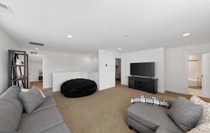 A modern living room with a sofa set, a black bean bag, a flat-screen TV, and a small cabinet. - Millville by the Sea- shuttle access Bethany beach (Millville)