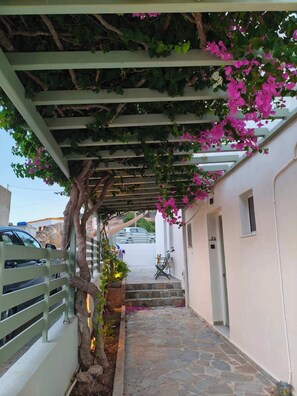 A narrow stone-paved pathway with a pergola covered in greenery and pink flowers, leading to a white building with a door marked 'E2'. - Seaview Apartment Galissas, Blue Lagoon Complex A9 (Galissas)