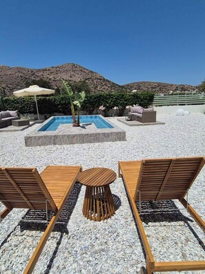 A pool area with lounge chairs, a table, and a mountain backdrop. - Seaview Apartment Galissas, Blue Lagoon Complex A9 (Galissas)