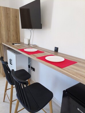 A modern kitchenette with a wooden countertop, two bar stools, a small refrigerator, and a flat-screen TV mounted on the wall. - Seaview Apartment Galissas, Blue Lagoon Complex A9 (Galissas)