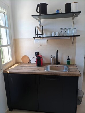A kitchen with a wooden countertop, a sink, a kettle, a coffee maker, and shelves above holding cups and glasses. - Seaview Apartment Galissas, Blue Lagoon Complex A9 (Galissas)