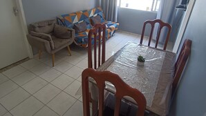 Een eetgedeelte met een tafel, stoelen, een bank en een raam met gordijnen.