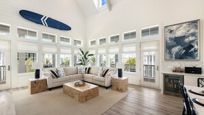 A spacious living room with a large sectional sofa, wooden coffee tables, and a dining area with a table and chairs. - Seas & Sunsets 201 LAK (Port Aransas)