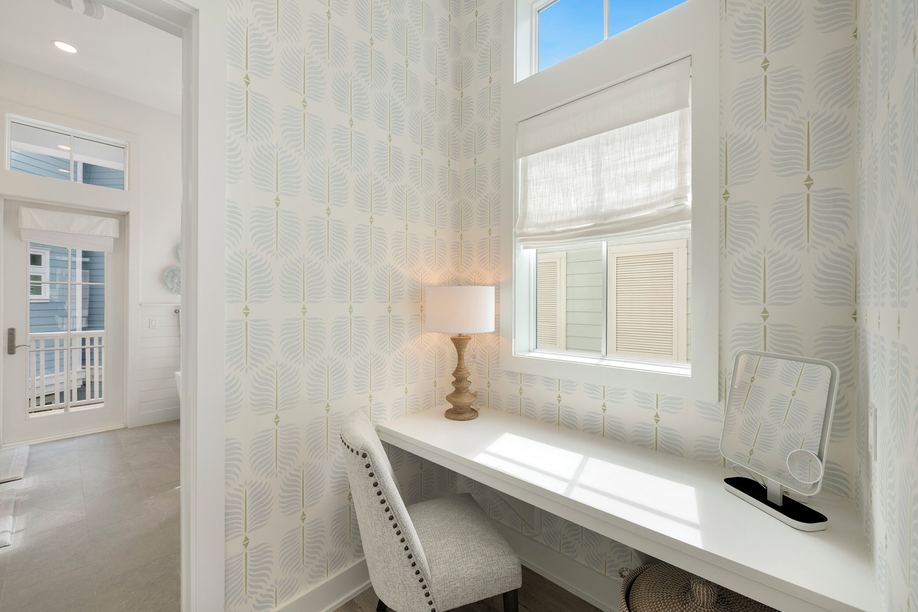 Ein Zimmer mit Fenster, Schreibtisch, Stuhl und Lampe.