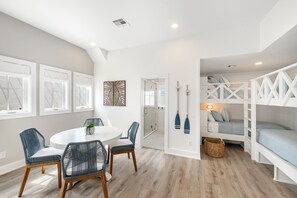 Ein modernes Interieur mit einem runden Esstisch, blauen Stühlen, einem weißen Sofa und einem Schlafplatz in der Schlaffküche mit einer Leiter.