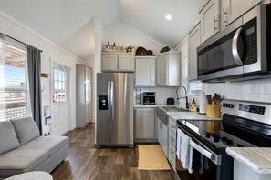 A compact kitchen with stainless steel appliances, a built-in oven, and a microwave.