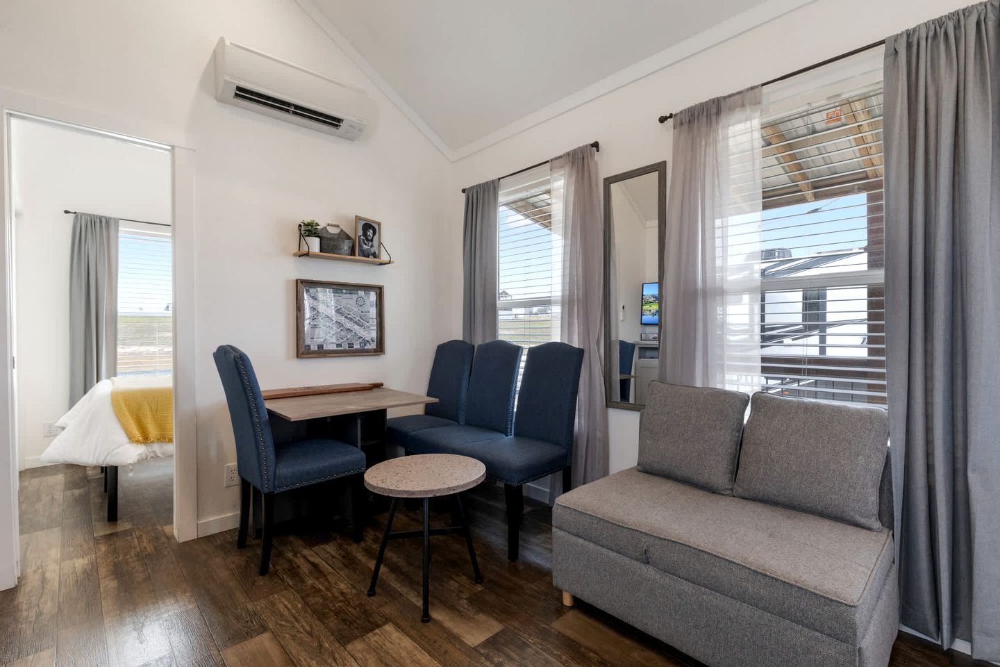 A compact living space with a sofa, two chairs, a small table, and a TV.