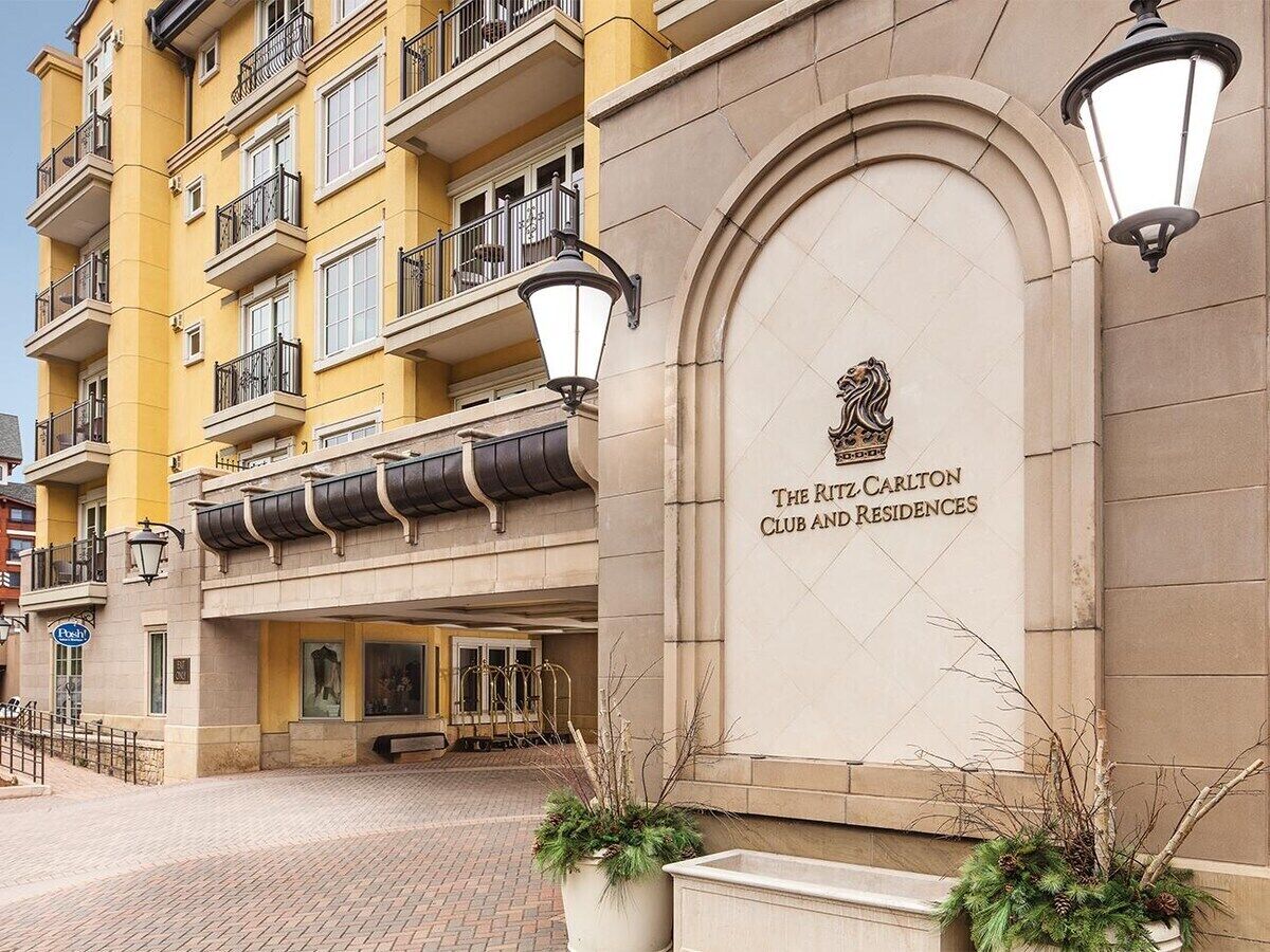Un edificio a più piani con un ingresso ben evidente, un cartello con la scritta 'The Ritz Carlton Club and Residences' e uno stile architettonico classico, caratterizzato da balconi e una facciata in pietra.