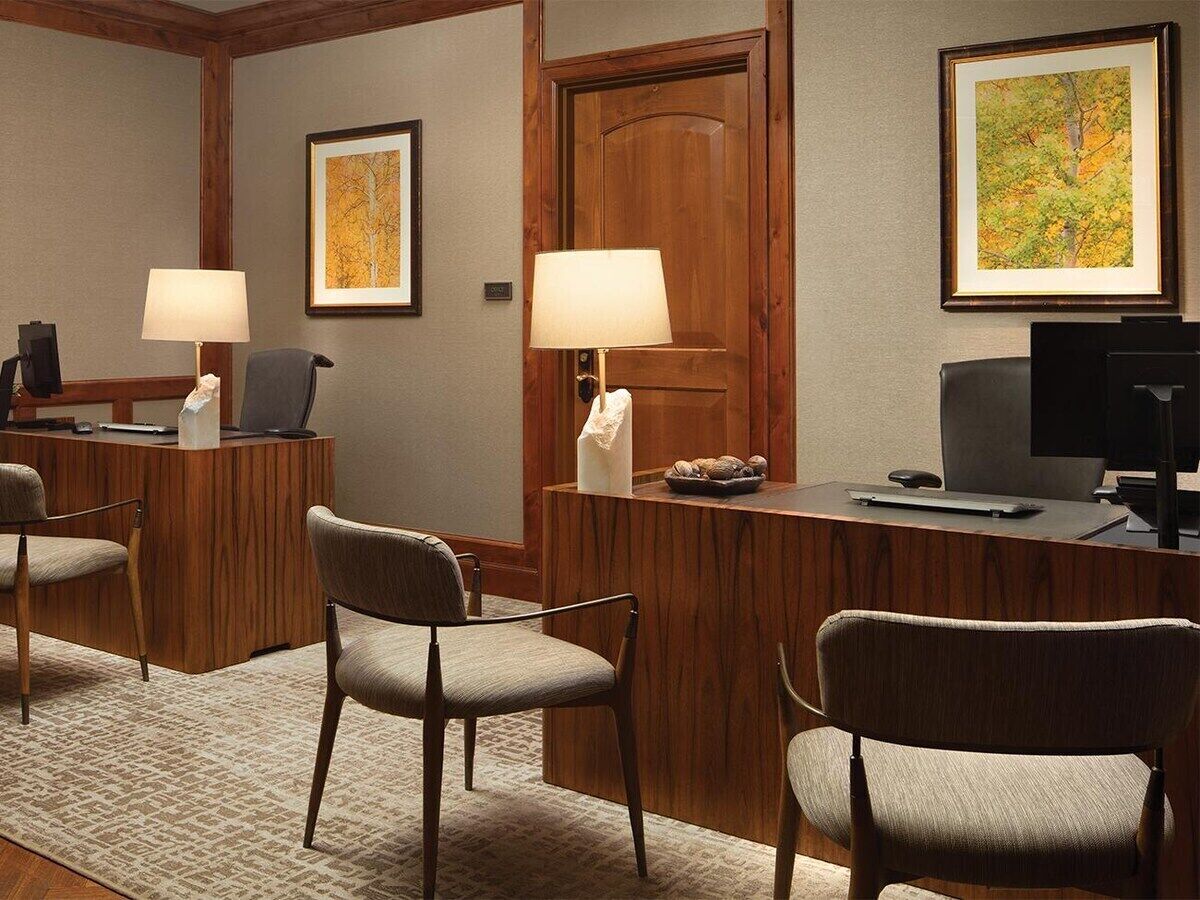 A reception desk with two chairs, a wooden door, and framed artwork on the walls.