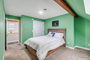 Un dormitorio con cama, puerta, ventana y un cuadro en la pared.