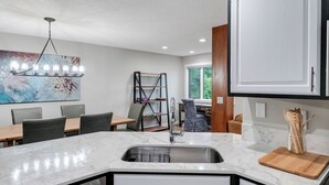 Une cuisine moderne dotée d’un plan de travail en marbre, d’un évier encastré et d’un coin repas avec une table et des chaises.