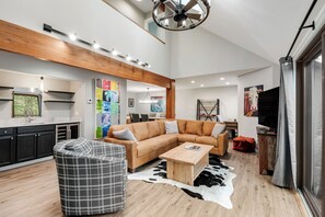 Un amplio salón con un sofá modular, una mesa de centro y un ventilador de techo moderno.