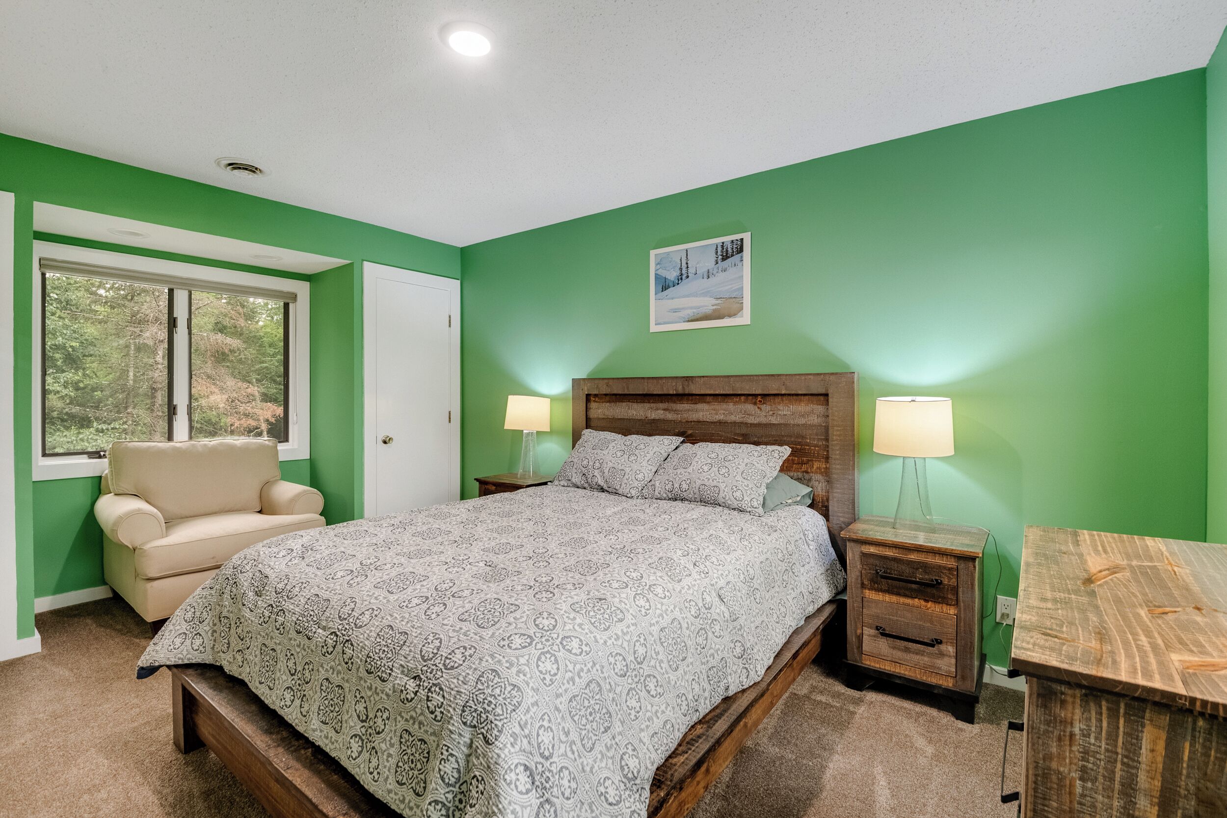 Une chambre à coucher comprenant un lit, une chaise, une table de chevet et une commode.