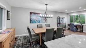 Un coin repas avec une table et des chaises en bois, un lustre et un tableau au mur.