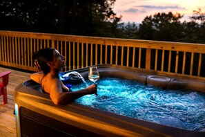 A person relaxing in a hot tub with a glass of white wine, surrounded by a wooden deck and a railing. - Stunning Dome with Barbecue and Hot-tub in Capon Bridge, West Virginia (Capon Bridge)