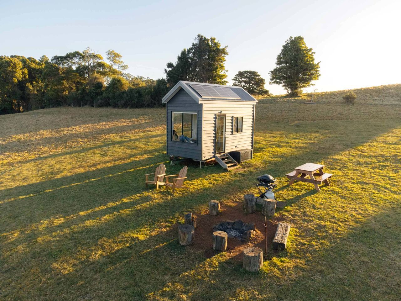 A small cabin with a porch, a fire pit, and outdoor seating.