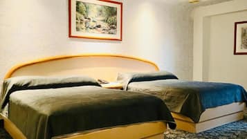 Una cama doble con cabecera de madera, dos almohadas y una manta azul.