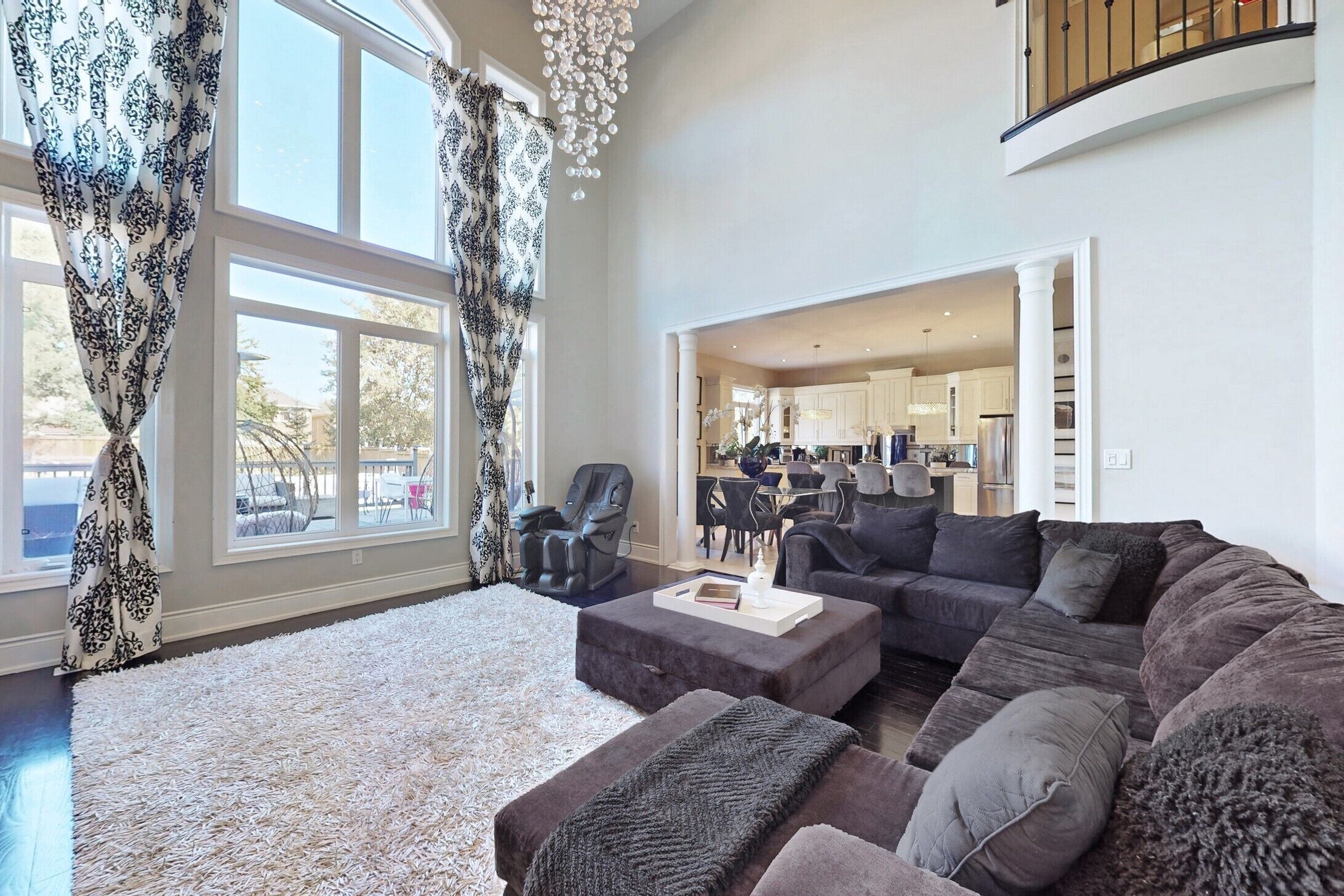 A spacious living room with a large sectional sofa, a coffee table, and a view into the kitchen.
