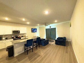 A modern kitchen with white cabinets, a microwave, and a dining area with blue chairs. - 3-bedroom townhome in delightful Falling Waters with AC (Falling Waters)