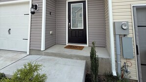 Ein zweistöckiges Wohnhaus mit Eingangstür, Garage und einem kleinen Vorgarten mit Fußmatte.