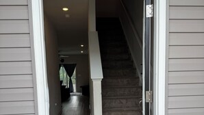 Blick durch eine Tür in ein Haus mit Teppichstufen und Holzboden.