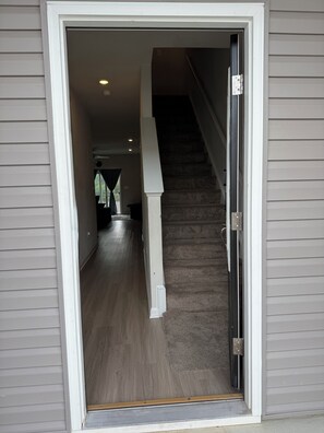 A view through a doorway into a home with a carpeted staircase and a wooden floor. - 3-bedroom townhome in delightful Falling Waters with AC (Falling Waters)