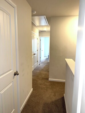A narrow hallway with carpeted floors, white walls, and a door on the left. - 3-bedroom townhome in delightful Falling Waters with AC (Falling Waters)