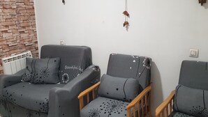 Ein Wohnzimmer mit zwei Sofas und einem Holzstuhl, einer Ziegelwand und einer Wanddekoration.