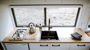 Una cucina compatta con piano cottura a gas, bollitore, lavello e una finestra vista spiaggia.