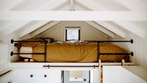 Una camera in stile dormitorio con un letto a castello, una piccola finestra e un soffitto bianco.