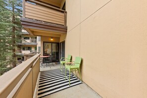 A balcony with a striped rug, two green chairs, and a table with chairs. - Vail Couple's Retreat:  Ski & Golf, Near Village (Vail)