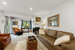 A living room with a brown leather sofa, a patterned ottoman, a wooden coffee table, and a fireplace. - Vail Couple's Retreat:  Ski & Golf, Near Village (Vail)