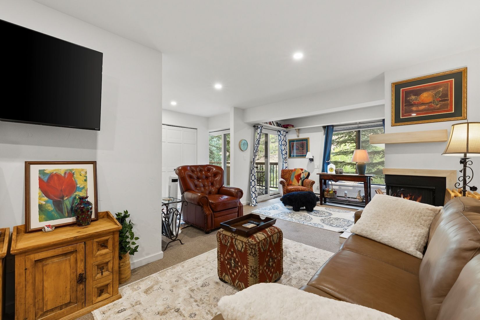A living room with a fireplace, leather sofas, a television, and a dining area with a table and chairs.