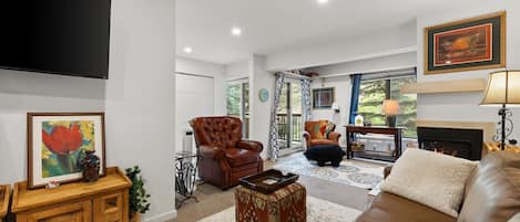 A living room with a fireplace, leather sofas, a television, and a dining area with a table and chairs.