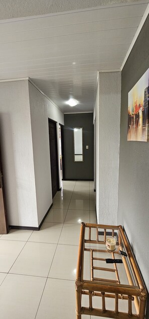 Un pasillo con un muro espejado, un banco de madera y un cuadro en la pared.