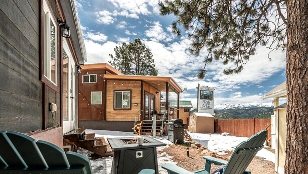 A patio area with Adirondack chairs, a fire pit, and a view of a mountain. - Rustic Tiny Home near Garden of the Gods, Perfect for a Weekend Getaway from Colorado Springs (Woodland Park)