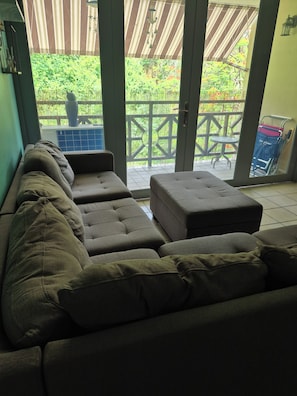 Un canapé modulable donnant sur un jardin, avec une porte-fenêtre coulissante.