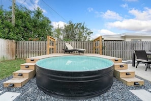 A hot tub with wooden steps leading to it, surrounded by a wooden fence and a grassy area. - Ocean Breeze Cottage: Private Oasis Near Boynton Beach & Delray Beach. (Boynton Beach)