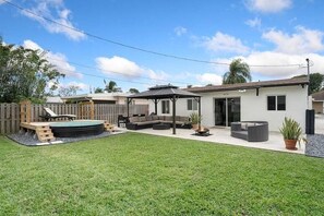 Ein Garten mit Whirlpool, überdachter Sitzgelegenheit und kleiner Terrasse.