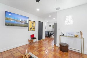 A modern interior with a flat-screen TV, a framed poster, a welcome sign, and a tiled floor.