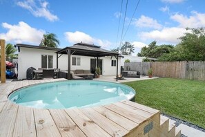A backyard with a swimming pool, a covered patio, and a fenced yard. - Ocean Breeze Cottage: Private Oasis Near Boynton Beach & Delray Beach. (Boynton Beach)