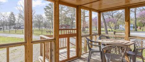 Un espace extérieur abrité, doté d’une terrasse en bois, de chaises en métal et d’une table.