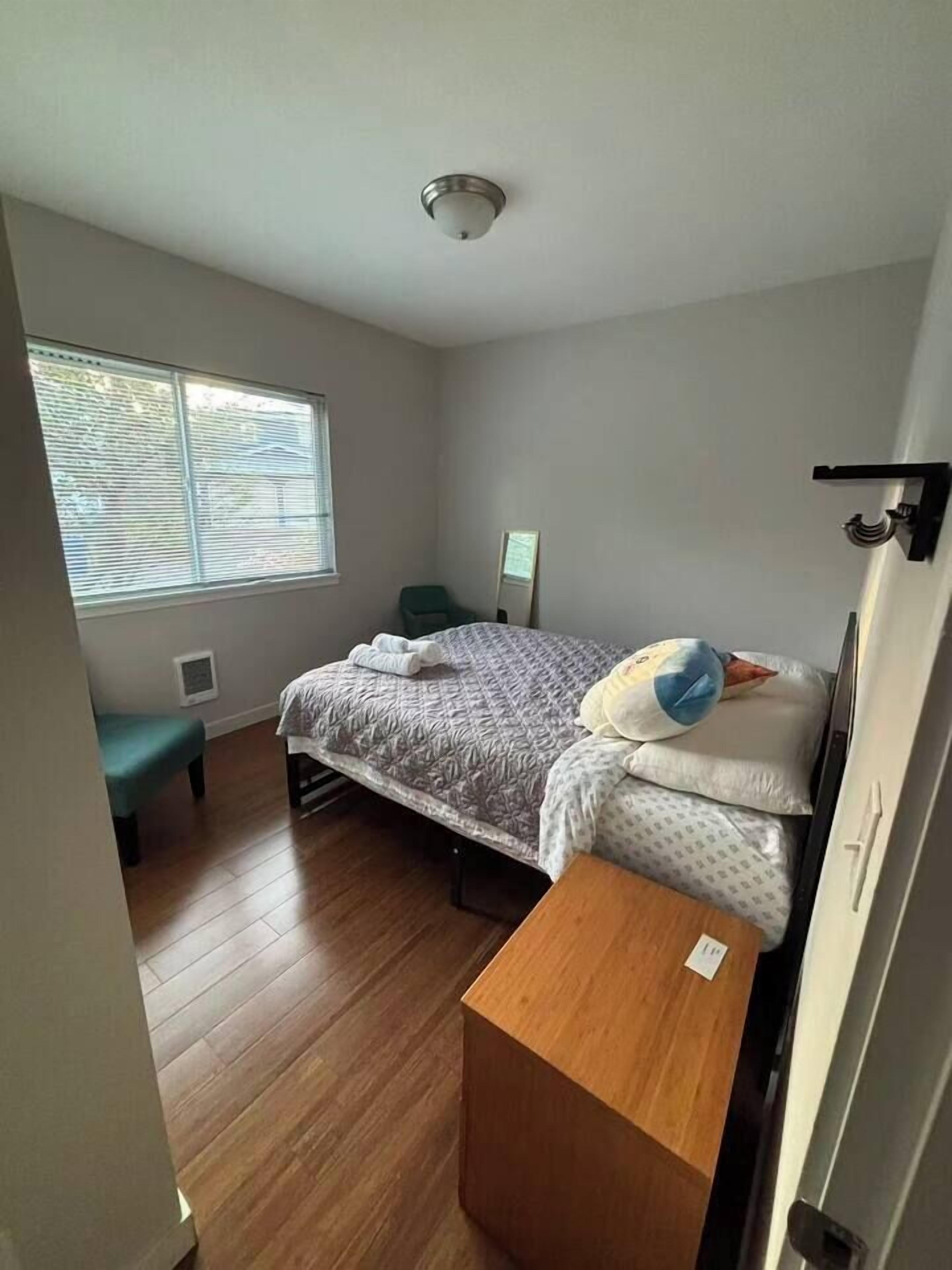 A bedroom with a bed, a bench, a window, and a door.