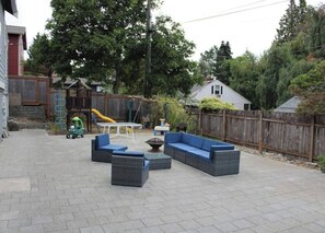 An outdoor patio area with a seating arrangement, a play structure, and a wooden fence. - Modern 6 Bedroom Getaway in North Seattle (Seattle)